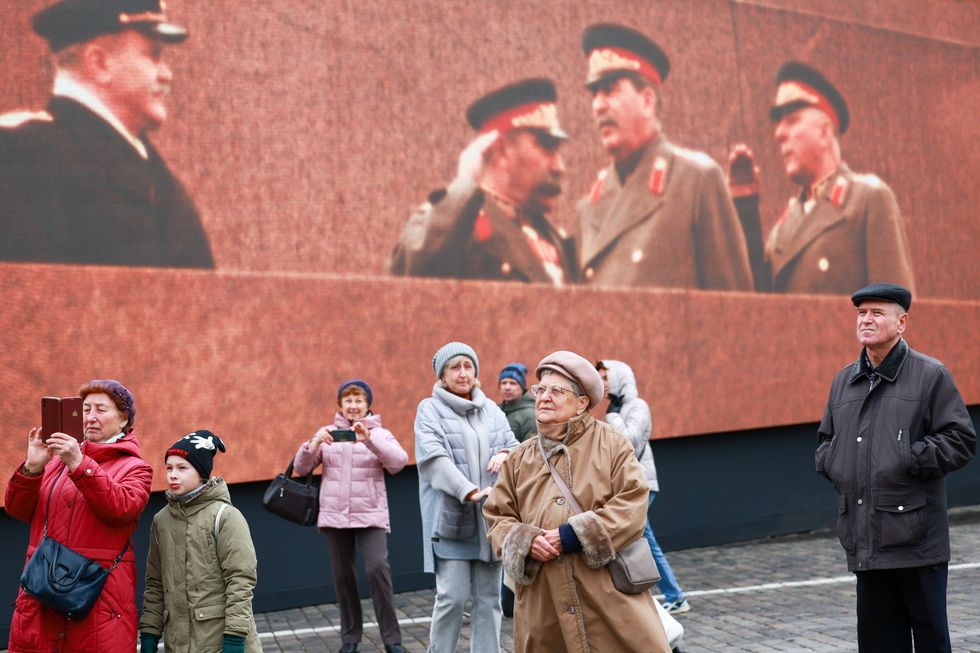photo of people looking at something with Stalin image behind them