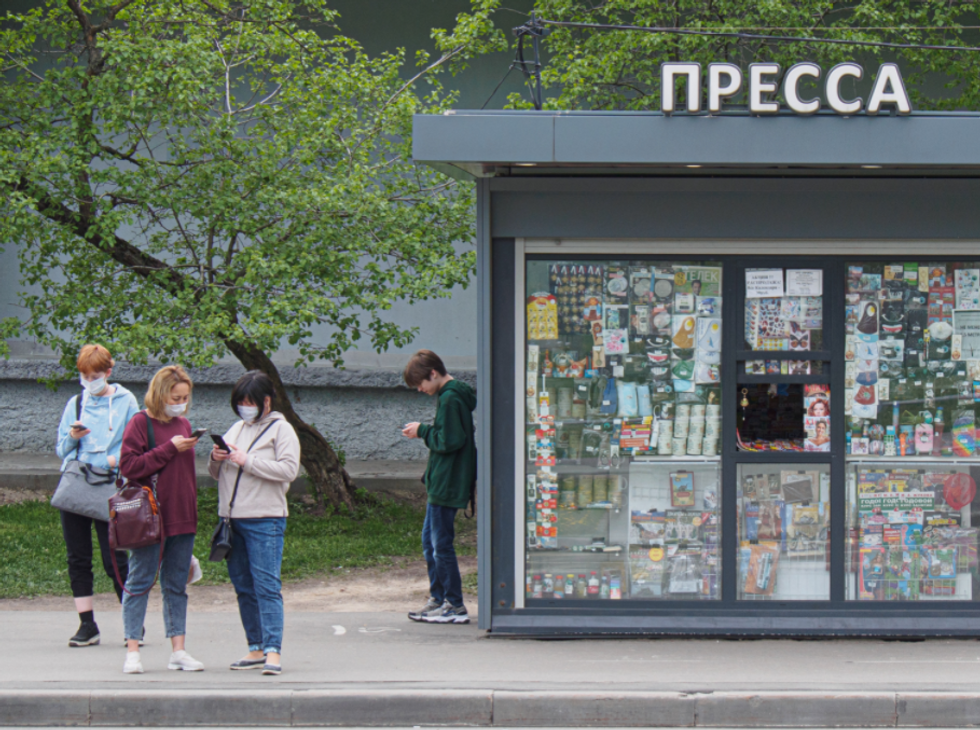 Photo of people on their smartphones next to a newsstand in Moscow, Russia