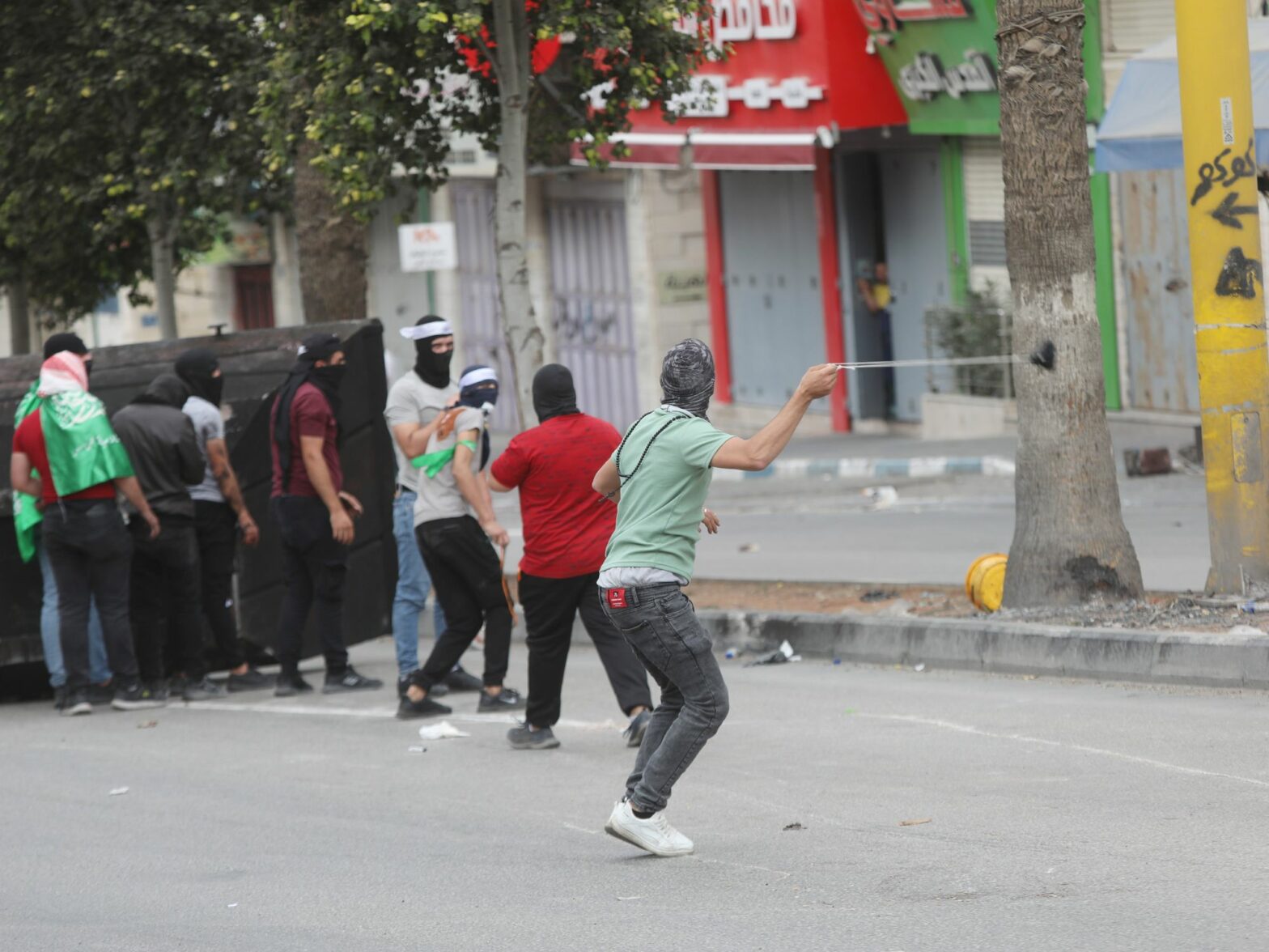 Photo of people Palestinians throwing stones toward Israeli troops