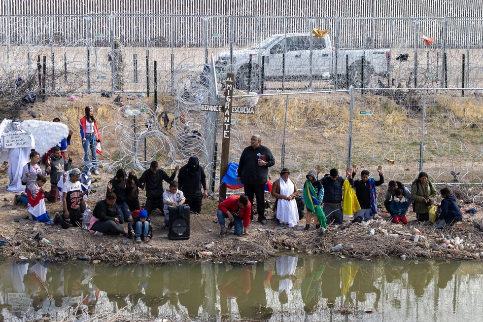 Photo of people waiting at a barbed wire fens to cross over into the U.S.