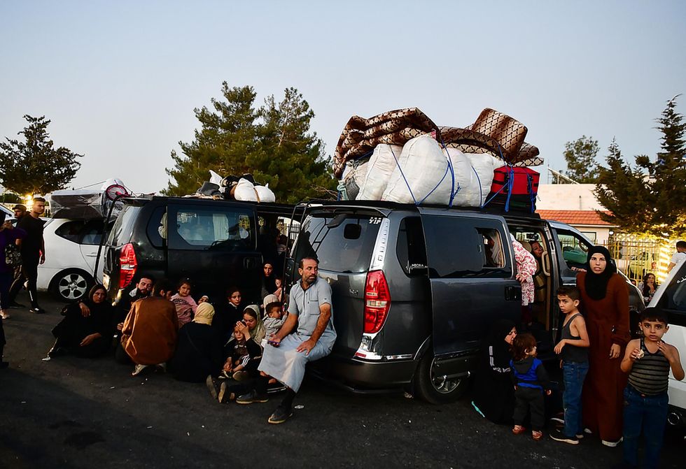 Photo of people waiting near their cars as they get ready to cross into Syria from Lebanon.
