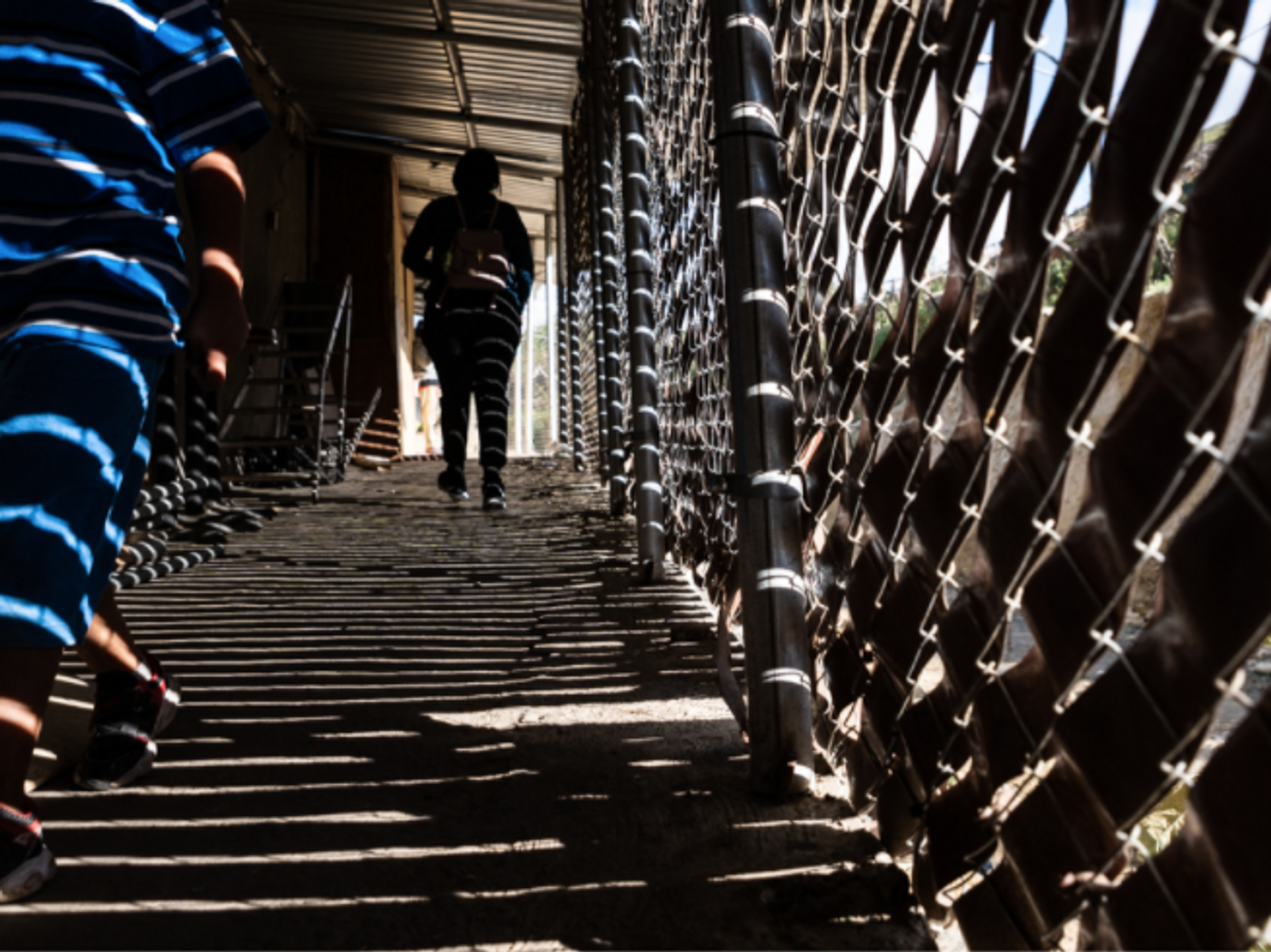 Photo of people walking alongside the border between Mexico and the United States in Tijuana