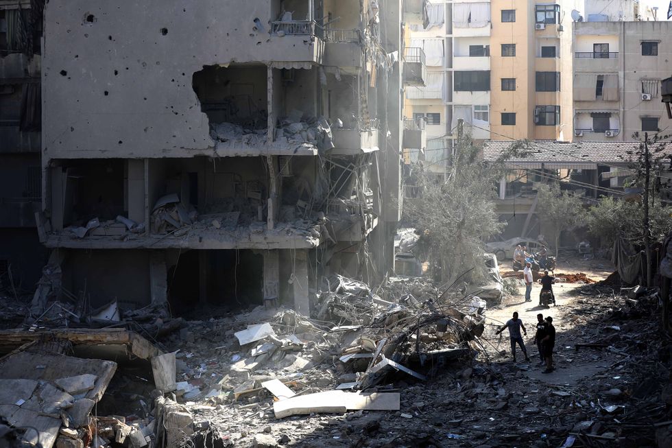 Photo of people walking among the rubble in a southern suburb of Beirut after Israeli airstrikes on Sept. 29.