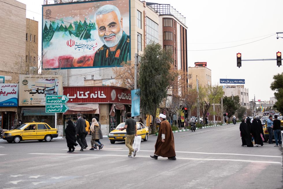 Photo of people walking by a portrait of the Iranian General Qassem Soleimani