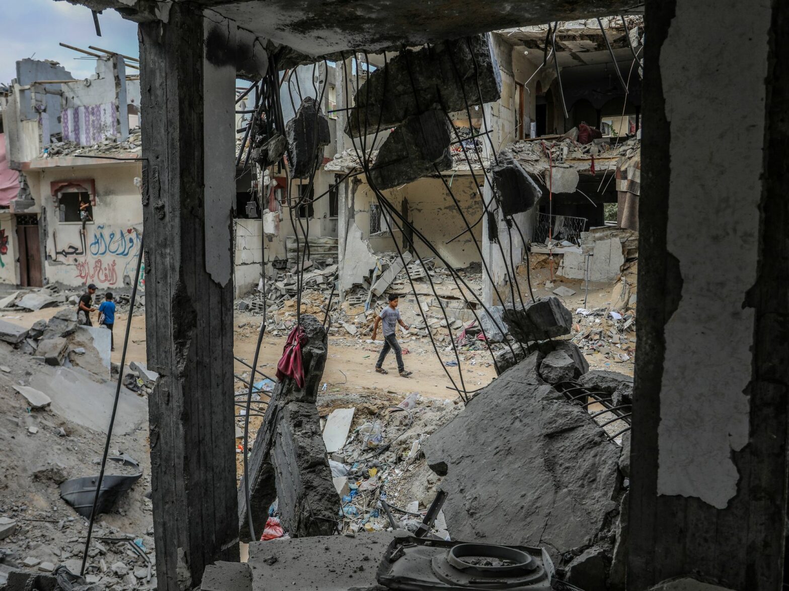 Photo of people walking by destroyed building in Rafah, Gaza