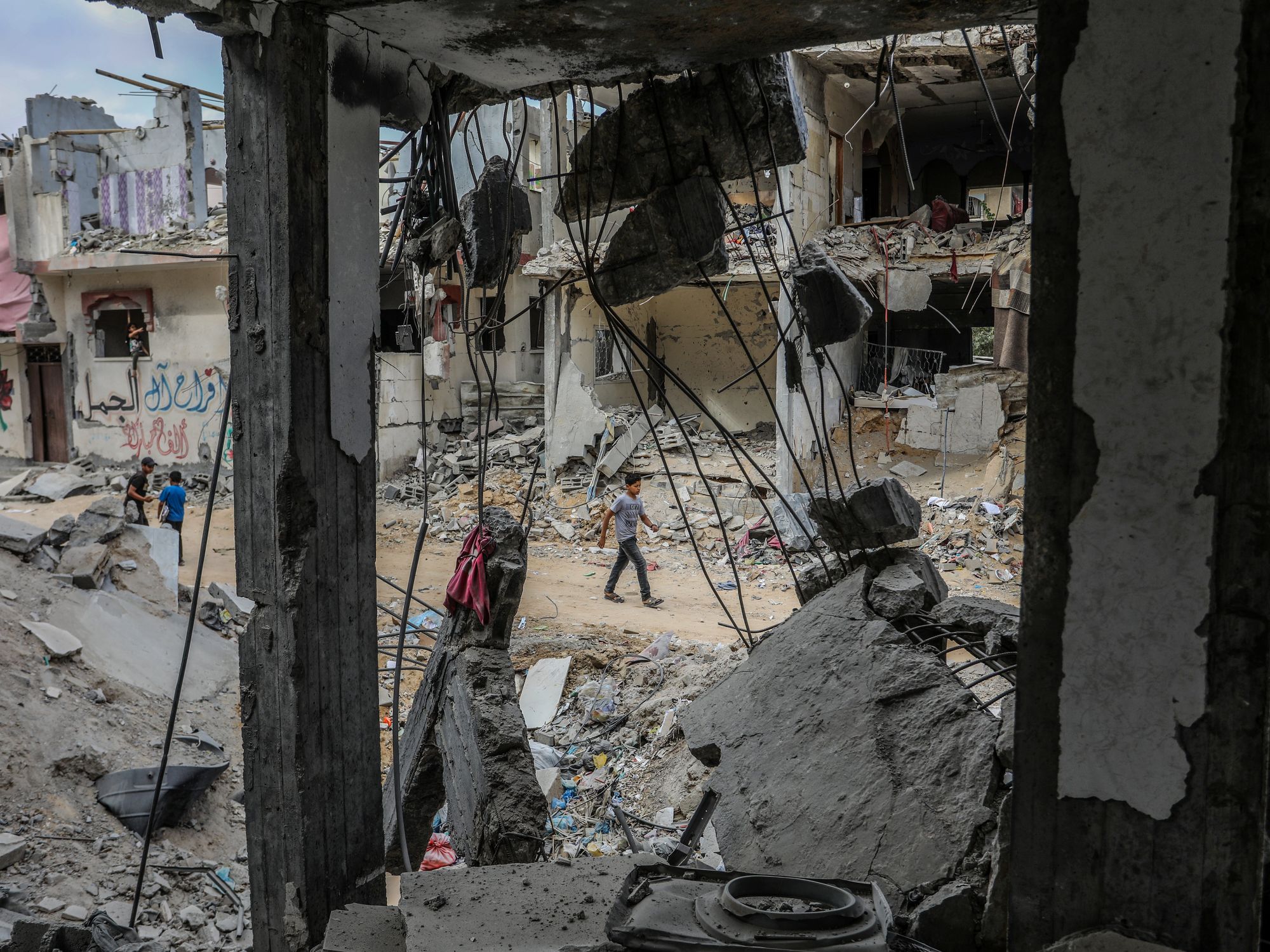Photo of people walking by destroyed building in Rafah, Gaza