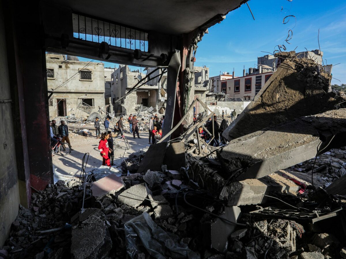 Photo of people walking by destroyed buildings in Rafah, Gaza, after an Israeli airstrike back in December.