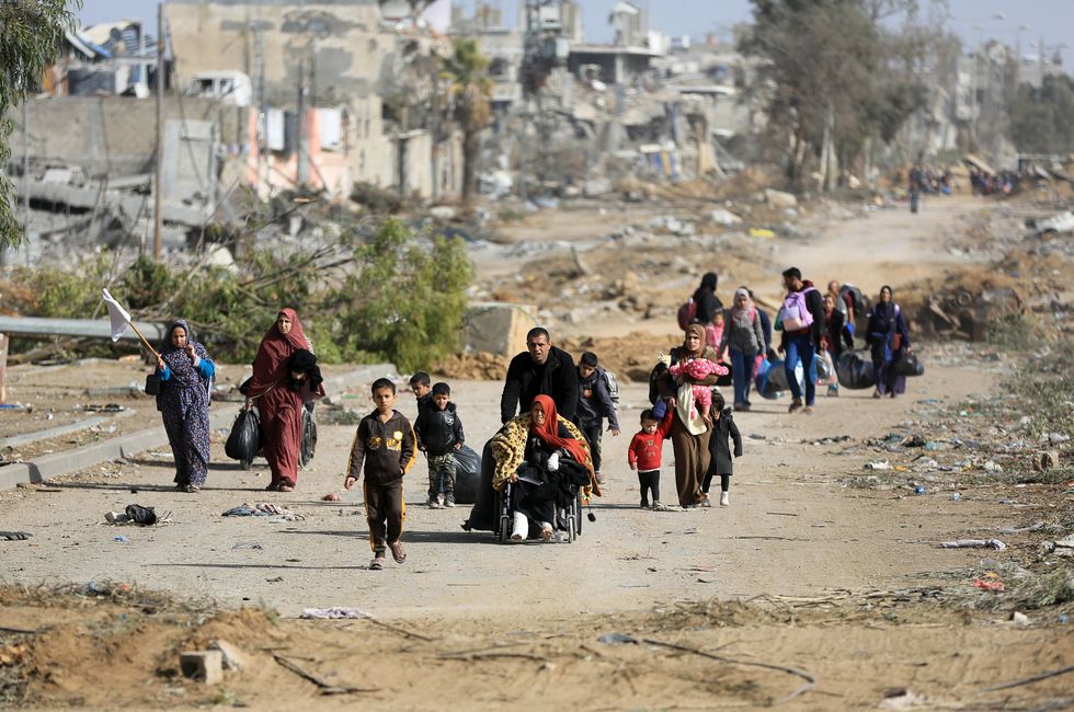 photo of people walking on a dirt road, with one man pushing a woman in a wheelchair