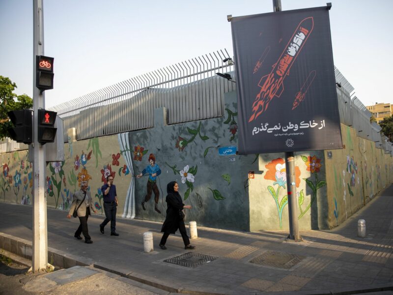Photo of people walking past a poster depicting Iranian missiles in downtown Tehran, on April 14, 2024.