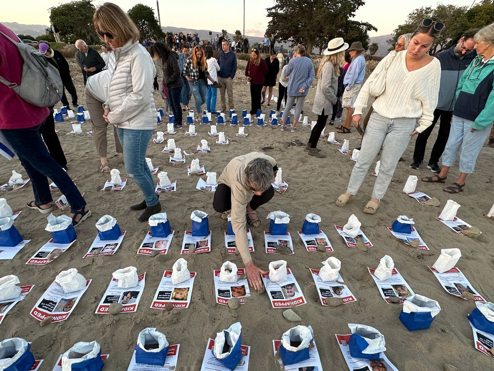 Photo of pictures of hostages held in Gaza laid out on the beach in Santa Barbara