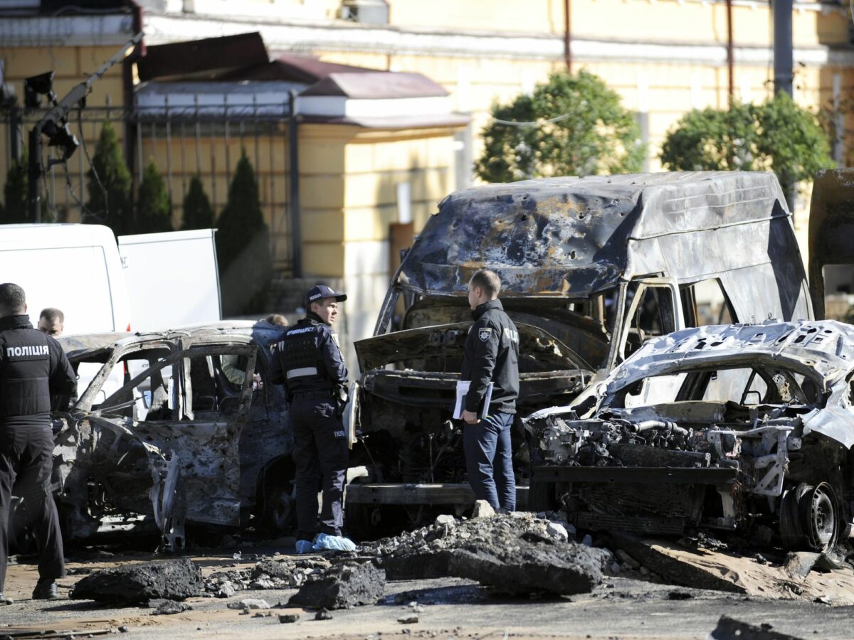 Photo of police forces looking at destroyed vehicles following Russian airstrikes on Kyiv