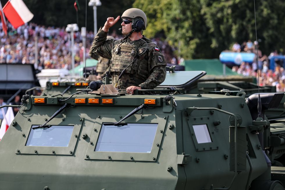photo of Polish servicemen present armoured vehicle at Wislostrada in the centre of Warsaw, the capital Poland during a military parade on Polish Army Day.