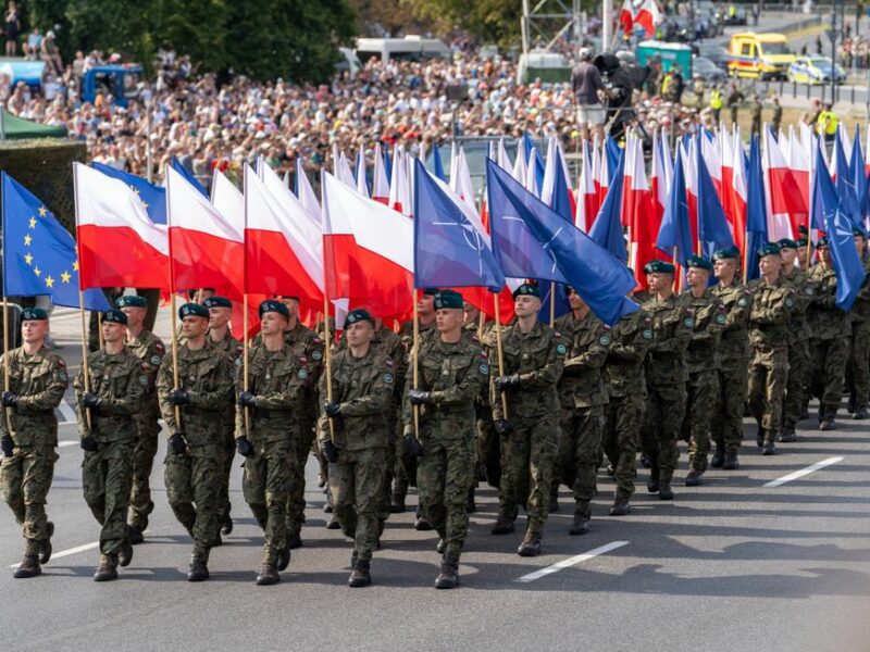 Photo of Polish soldiers marching with Polish and NATO flags in Warsaw on Aug. 15