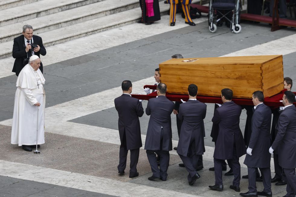 Photo of Pope Francis before the casket of Pope Benedict XVI