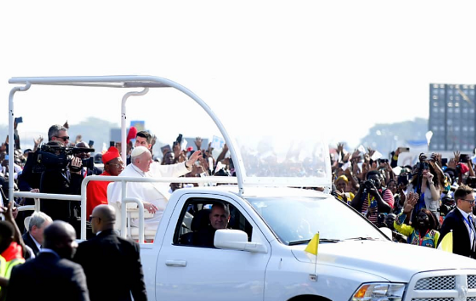 Photo of Pope Francis waving to a crowd from the top of a car in Kinshasa