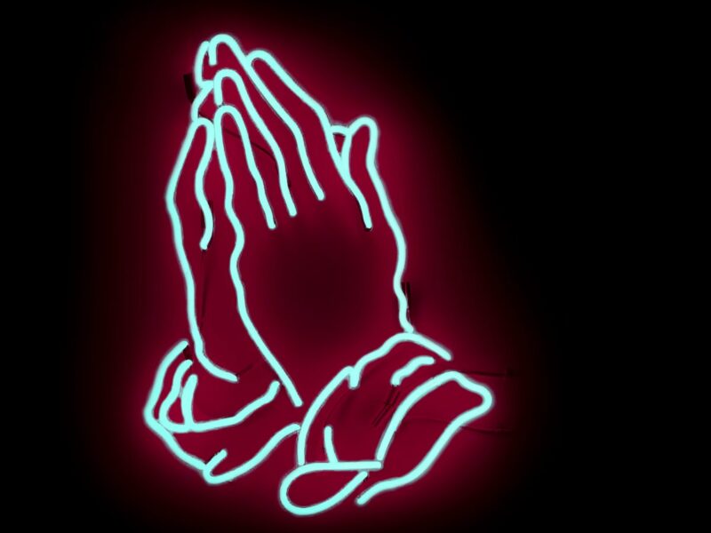 Photo of praying hands in neon sign