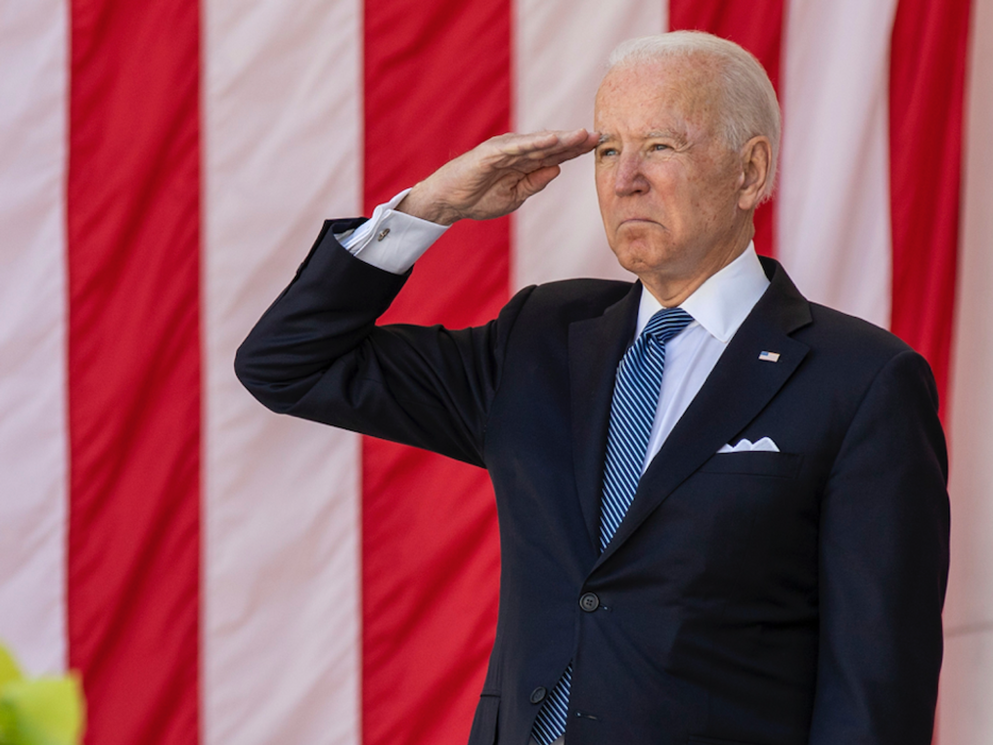 Photo of President Biden saluting with a U.S. flag as backdrop