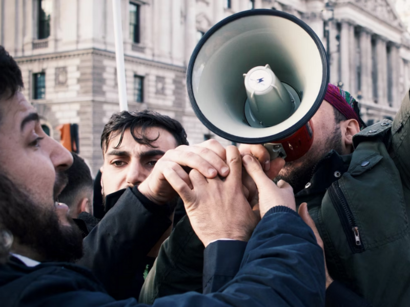 Photo of protesters arguing, with one chanting in a megaphone