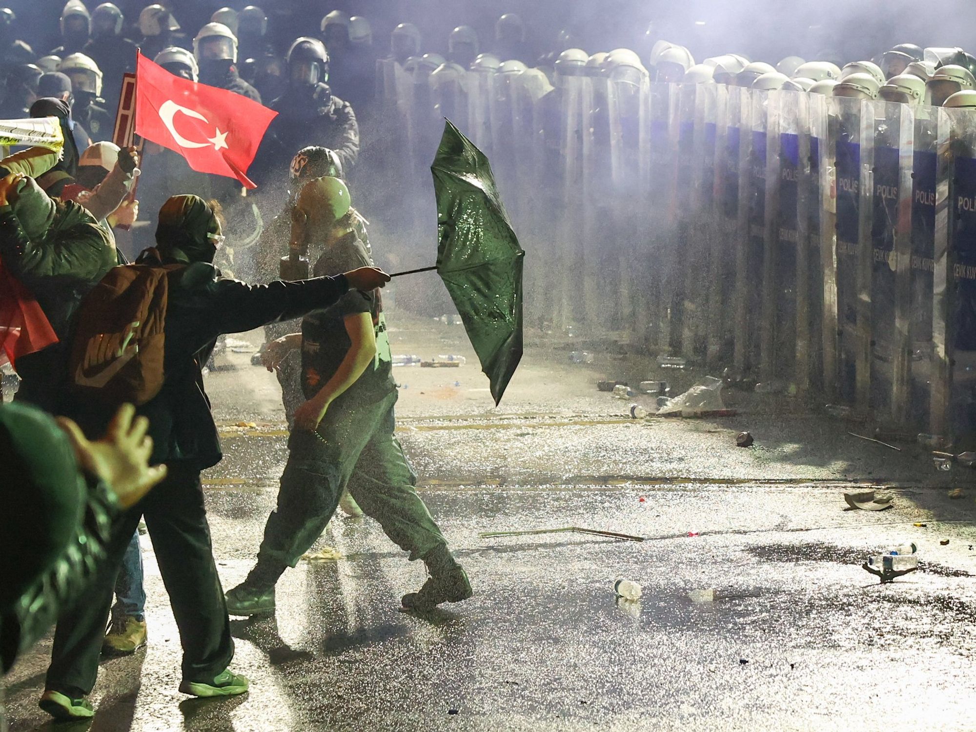 photo of protesters facing police with a turkish flag