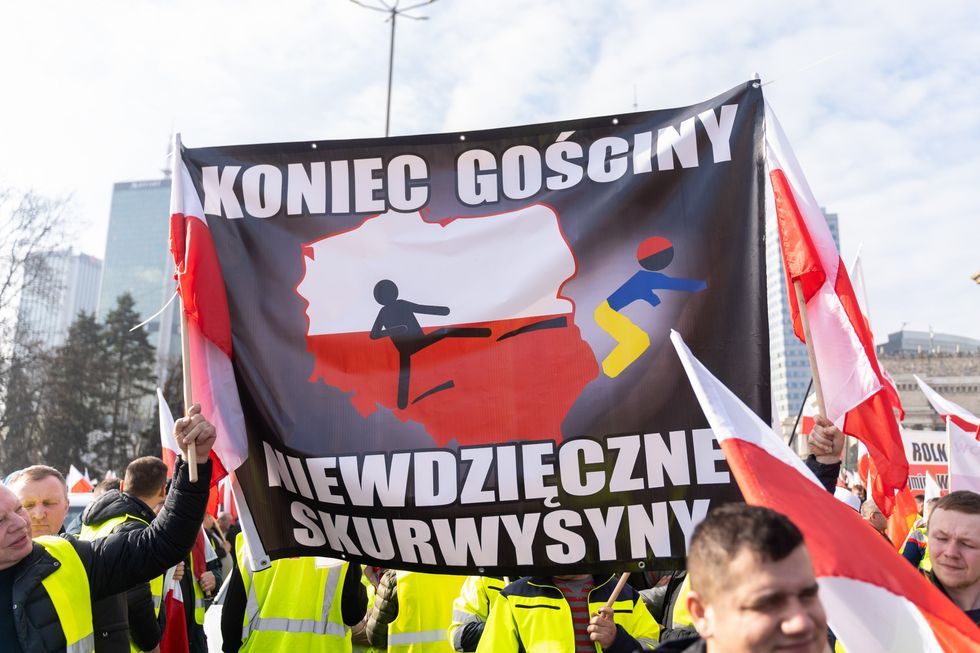 Photo of protesters holding an an anti-Ukrainian banner that says ''No more hospitality, you ungrateful bastards'' during a demonstration.