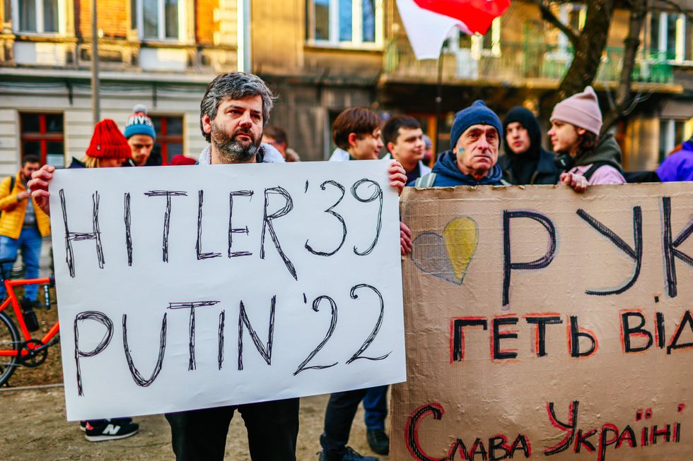 Photo of protesters holding sign that says: Hitler 39, Putin 22