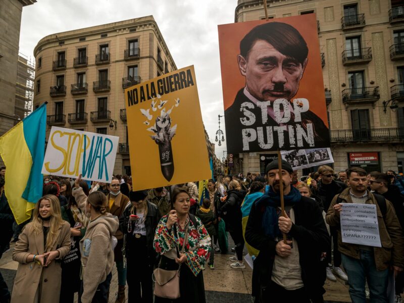 photo of protesters holding signs, including one of putin as hitler