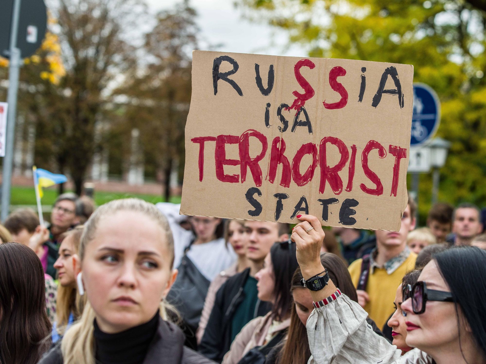 photo of protesters holding up a sign that reads Russia is a terrorist state