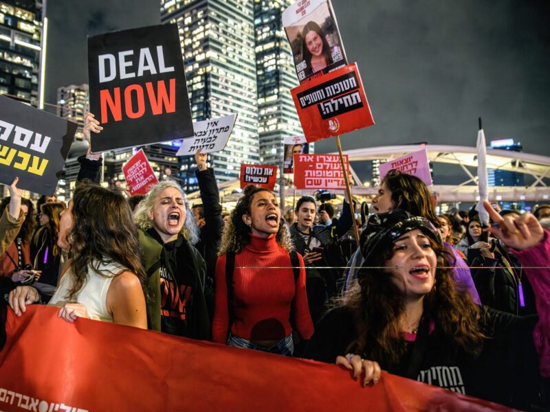 photo of protesters holding up signs in english and hebrew
