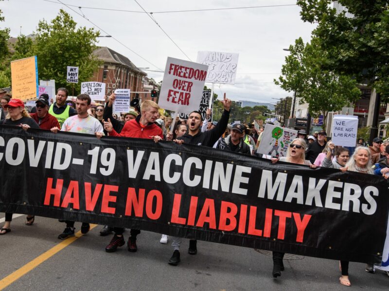 Photo of protesters in Australia holding a sign that says "Covid-19 vaccine makers have no liability"