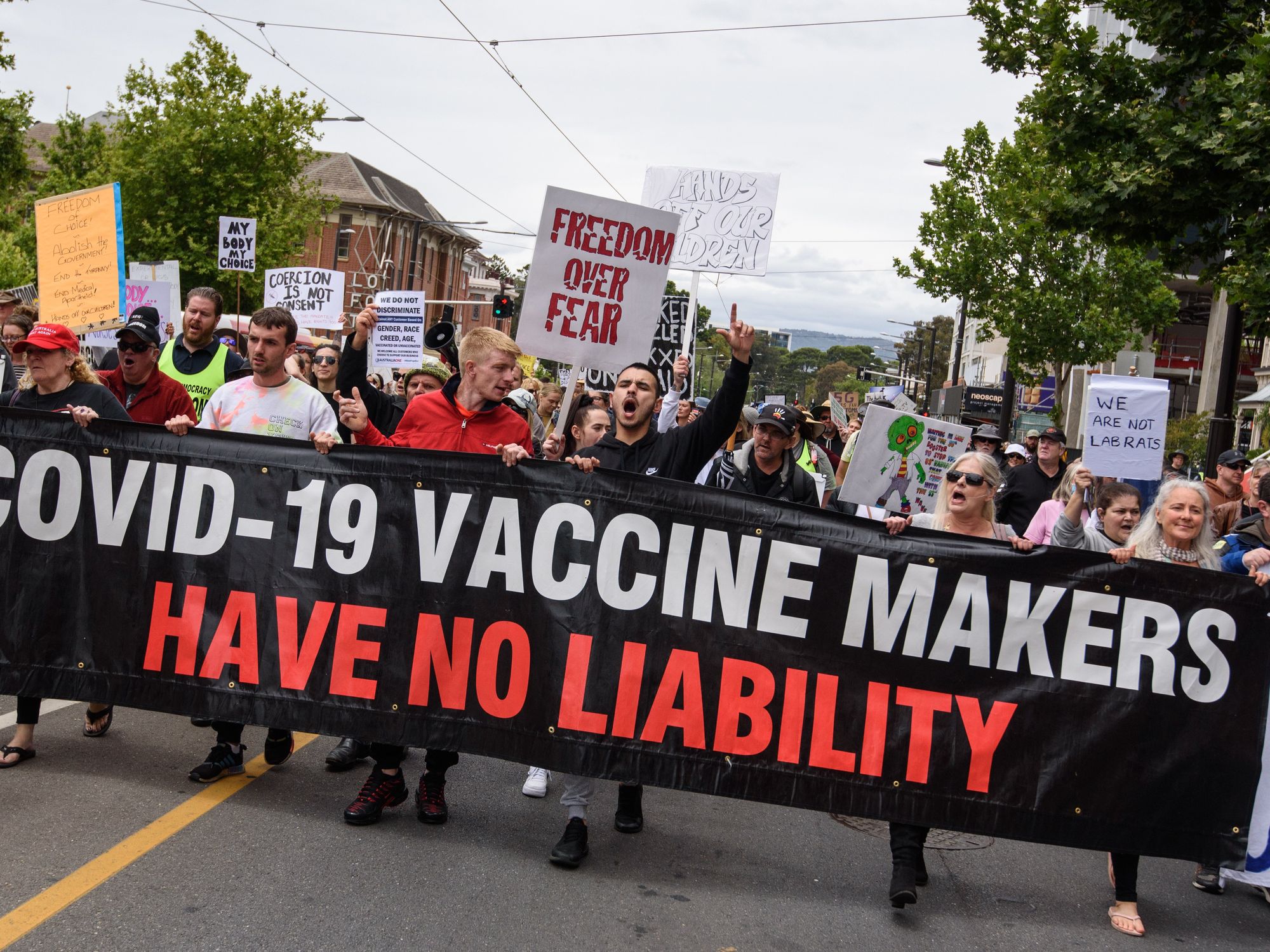 Photo of protesters in Australia holding a sign that says "Covid-19 vaccine makers have no liability"