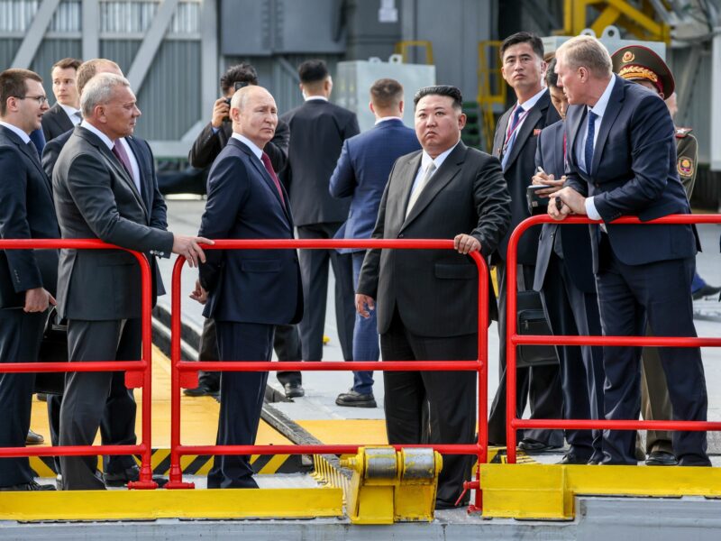 photo of putin and kim in front of a red guard rail
