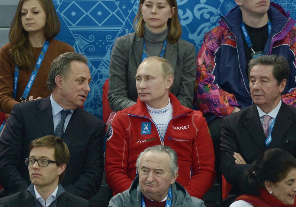photo of Putin watching from the stands with officials on either side of him