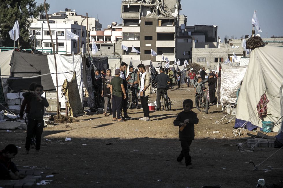 Photo of refugees walking near tents at a camp in Yarmouk, Gaza, on Nov. 3