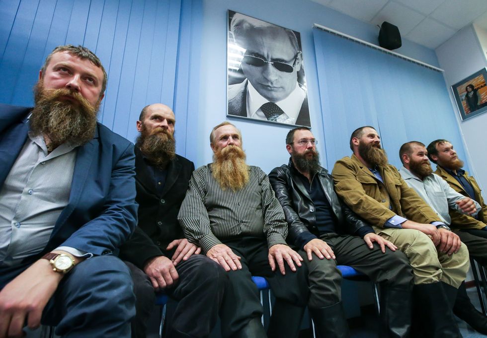 photo of Russian men with beards with a photo of clean-shaven Putin behind