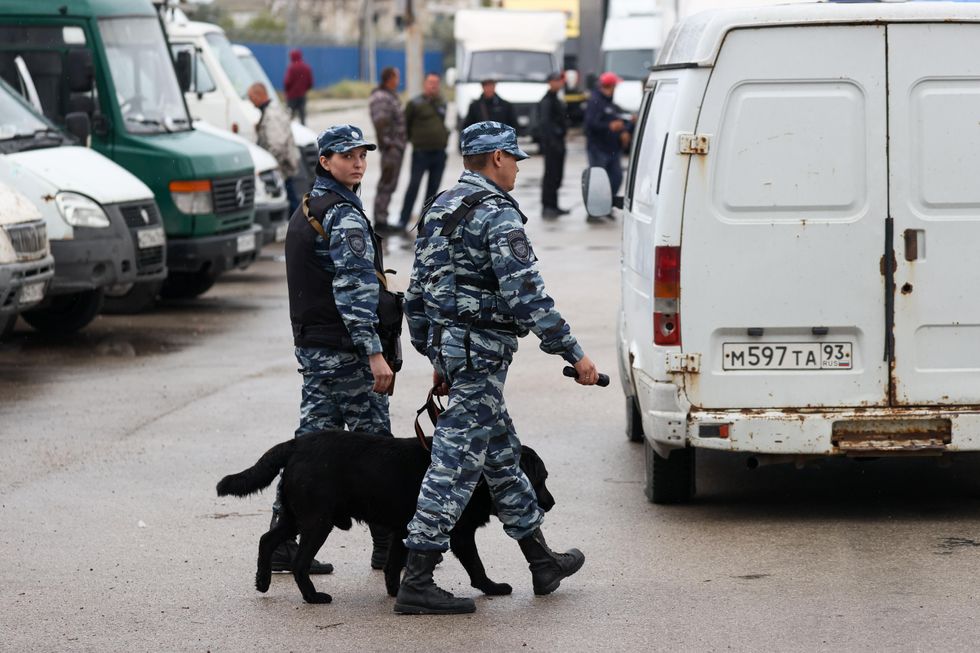 Photo of Russian personnel and a dog searching vehicles at an entrance to a ferry line across the Kerch Strait at the Port of Krym.
