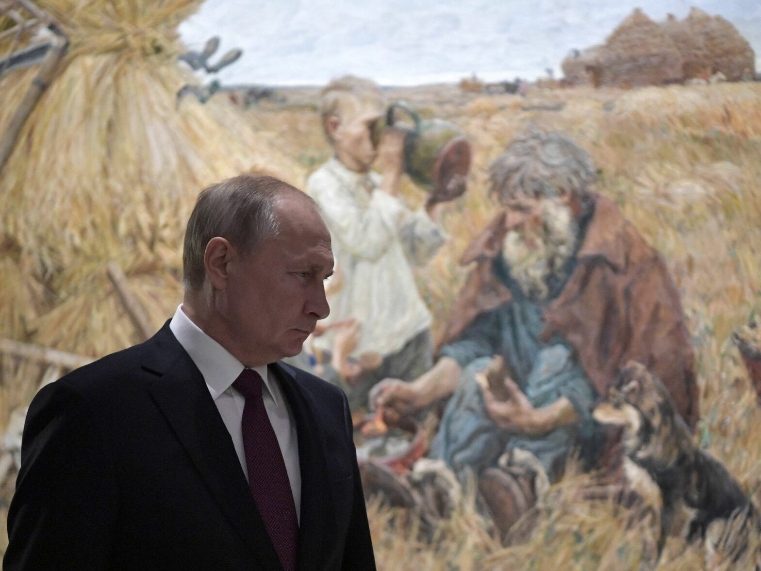 Photo of Russian President Vladimir Putin visiting Moscow's Manege Central Exhibition Hall, with an oil painting depicting farmers in the background