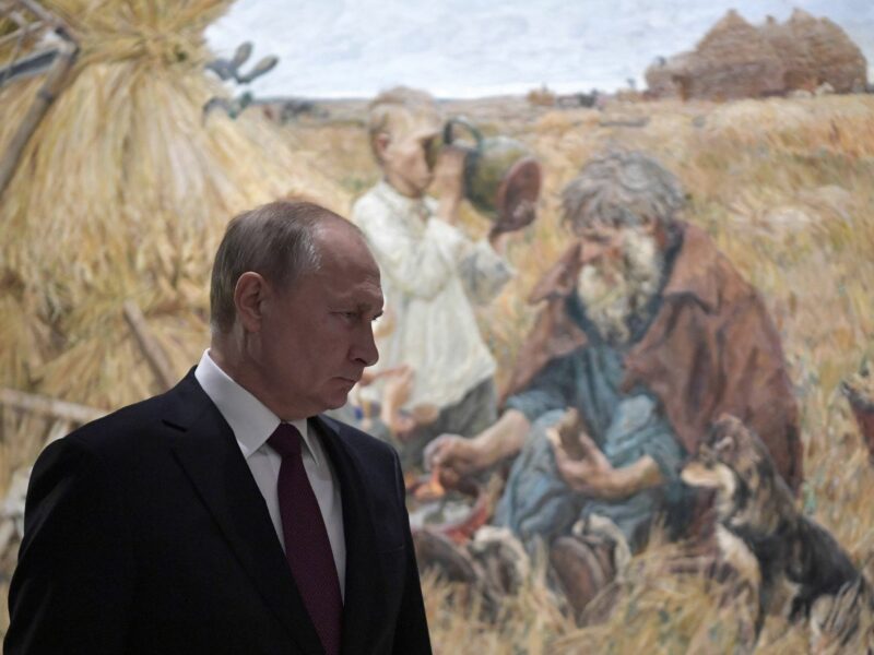 Photo of Russian President Vladimir Putin visiting Moscow's Manege Central Exhibition Hall, with an oil painting depicting farmers in the background