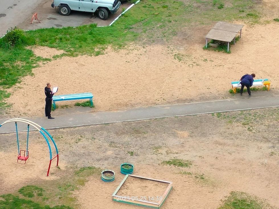Photo of Russians repainting blue-yellow-colored benches under police supervision in Omsk