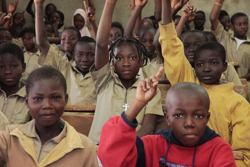 Photo of schoolchildren raising their hands at a school in Burkina Faso