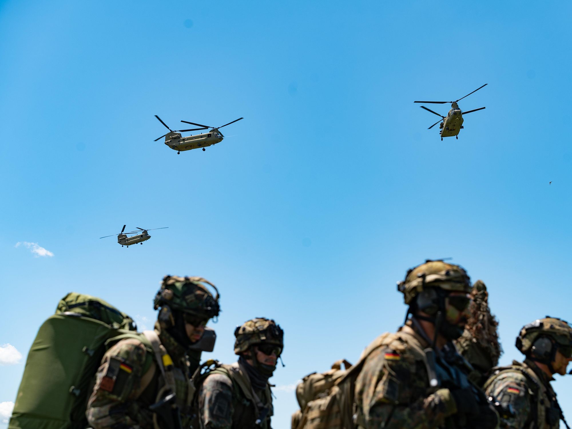 photo of soldiers marching with helicopters overhead