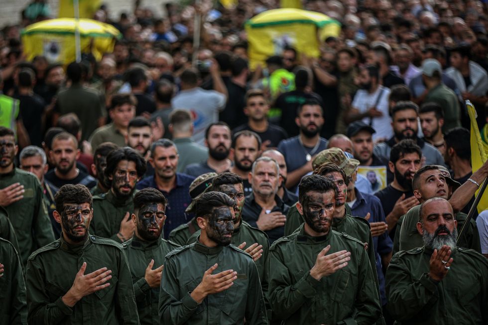 Photo of soldiers with their hands on their hearts as they attend the funeral of two Hezbollah fighters killed in an Israeli missile strike in the southern Lebanese village of Khirbet Silem on Oct. 10.