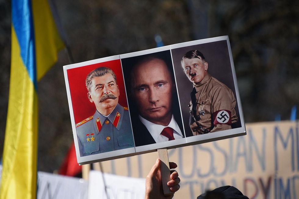 Photo of someone holding a sign at a pro-Ukraine protest comparing Russia's President Vladimir Putin to Joseph Stalin and Adolf Hitler.