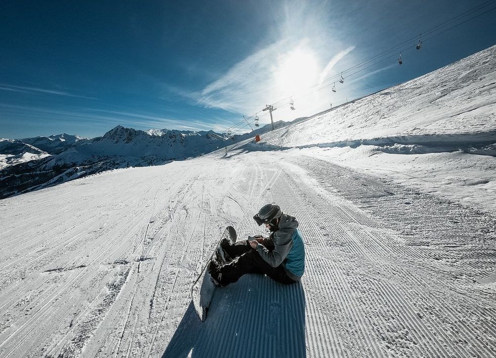 Photo of someone on snowboard looking at his phone