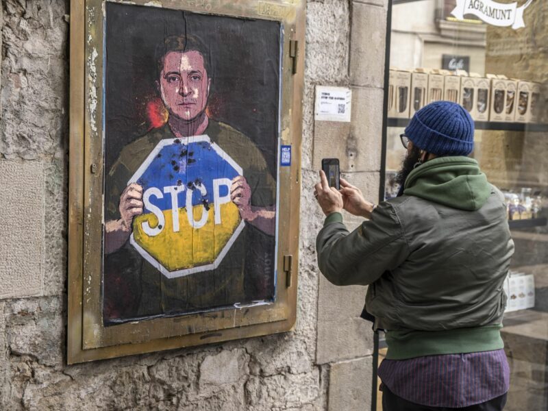 Photo of someone taking a photo of a painting of President Zelensky saying STOP to the war.