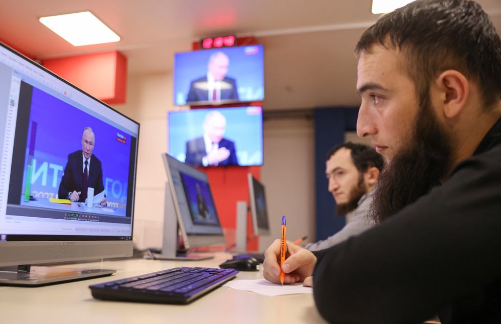 photo of someone watching putin on screen and taking notes with a pen