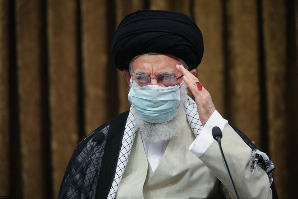 photo of Supreme Leader Ayatollah Ali Khamenei saluting with his hand at a military university graduation ceremony