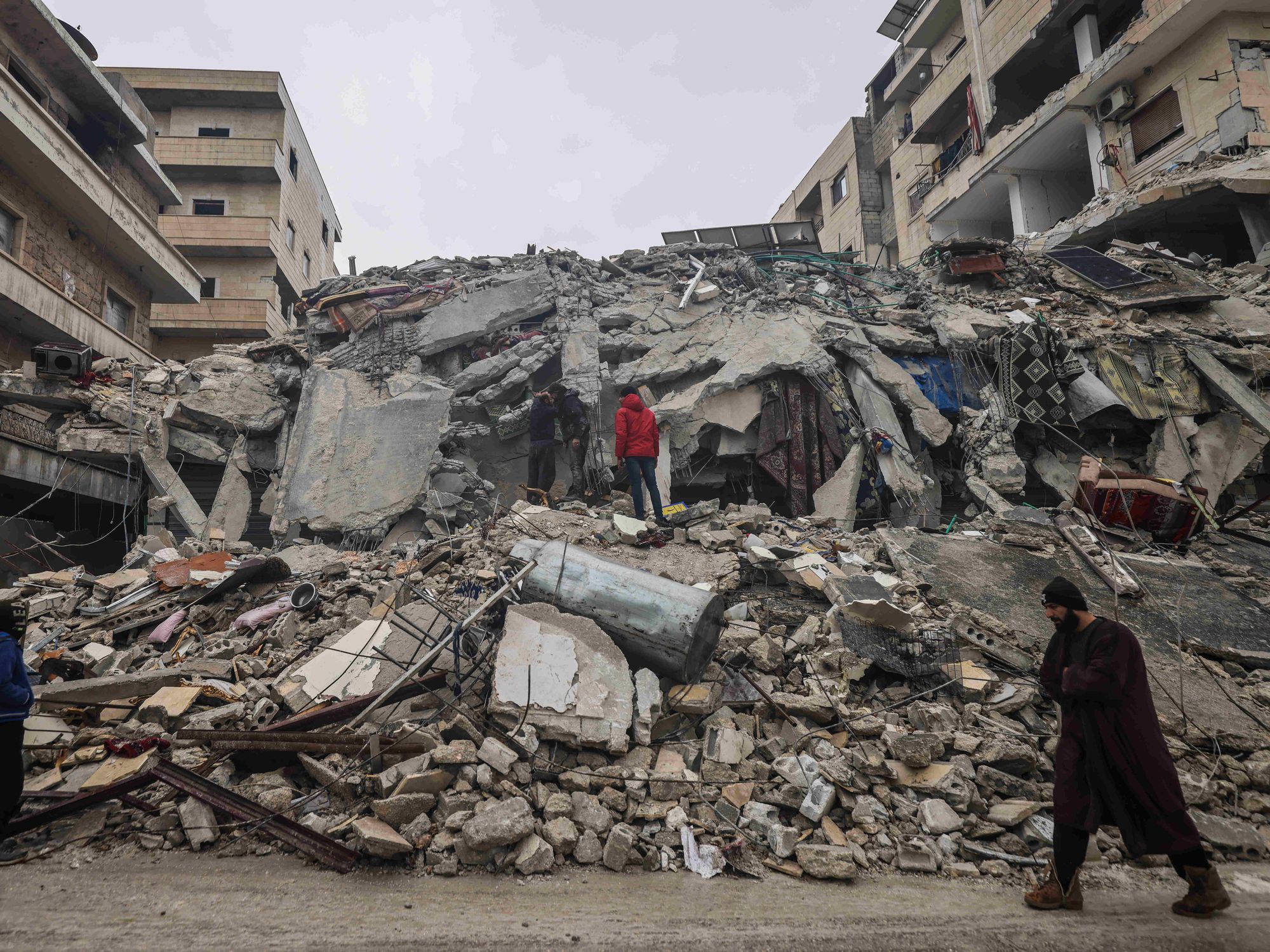 Photo of Syrian civilians inspecting a destroyed residential building in Idlib after the earthquake