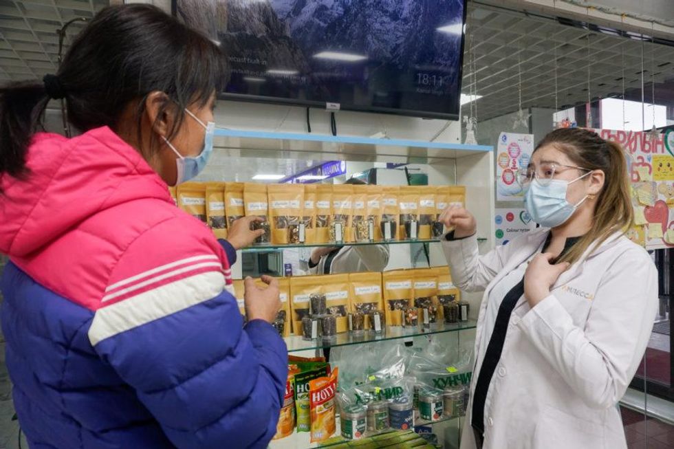 Photo of Tergel Munkhsaikhan, head of Sud-Pharm pharmacy in Orkhon province, explains the uses and effectiveness of traditional medicines to Oyu-Erdene Battumur.
