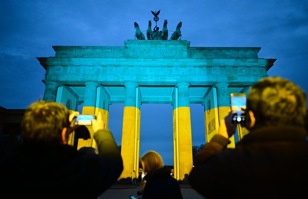 photo of The Brandenburg Gate, illuminated in the Ukrainian national colors of blue and yellow, before a commemorative event marking the third anniversary of the Russian invasion of Ukraine.