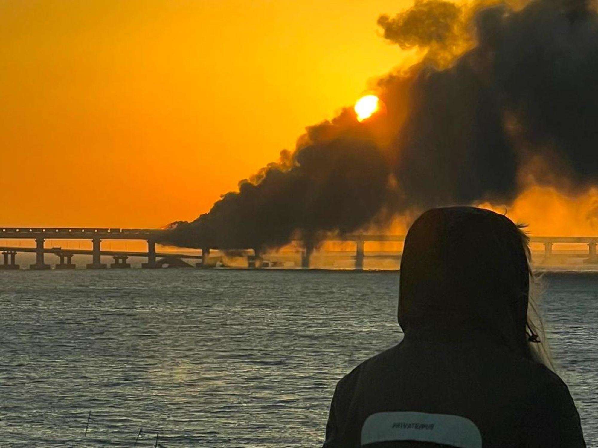Photo of the sun setting through the smoke caused by the the fire on the bridge linking Crimea to mainland Russia following an explosion on Oct. 8
